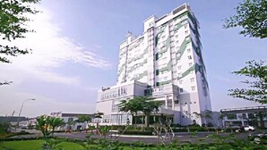 Un moderno hotel de rascacielos con varios pisos, ventanas amplias y un patio central con vegetación.