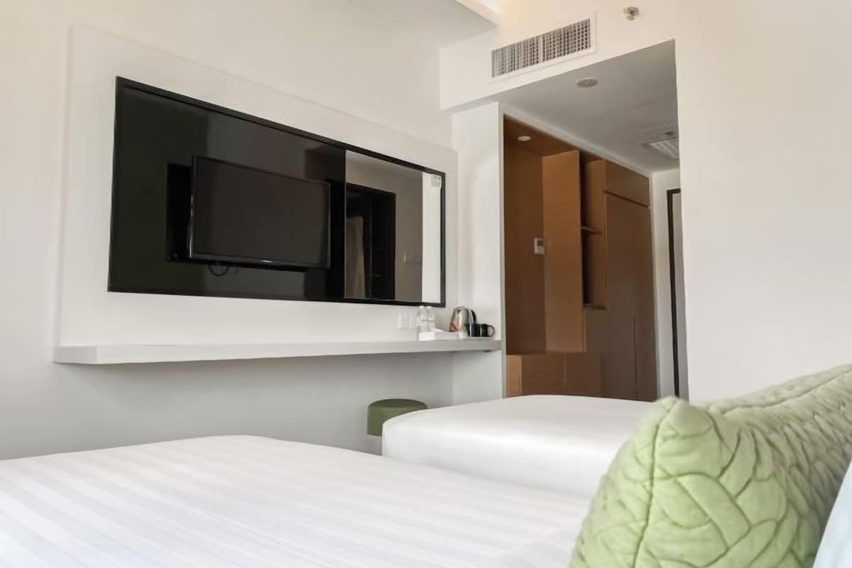 A hotel room with a bed, a television mounted on the wall, and a door leading to another room.