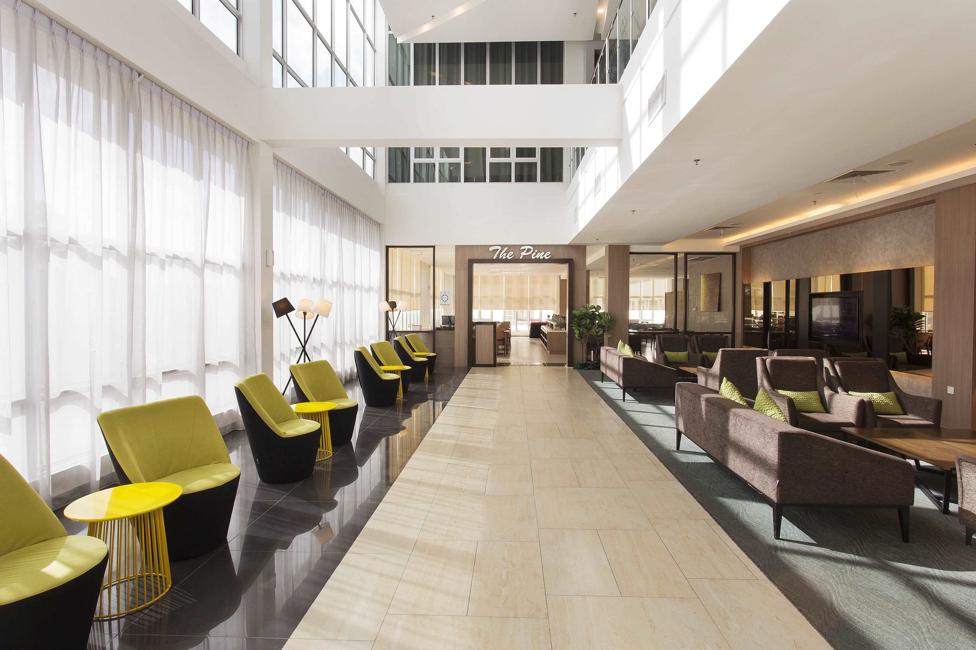 A spacious lobby with a high ceiling, a reception desk, and seating areas.