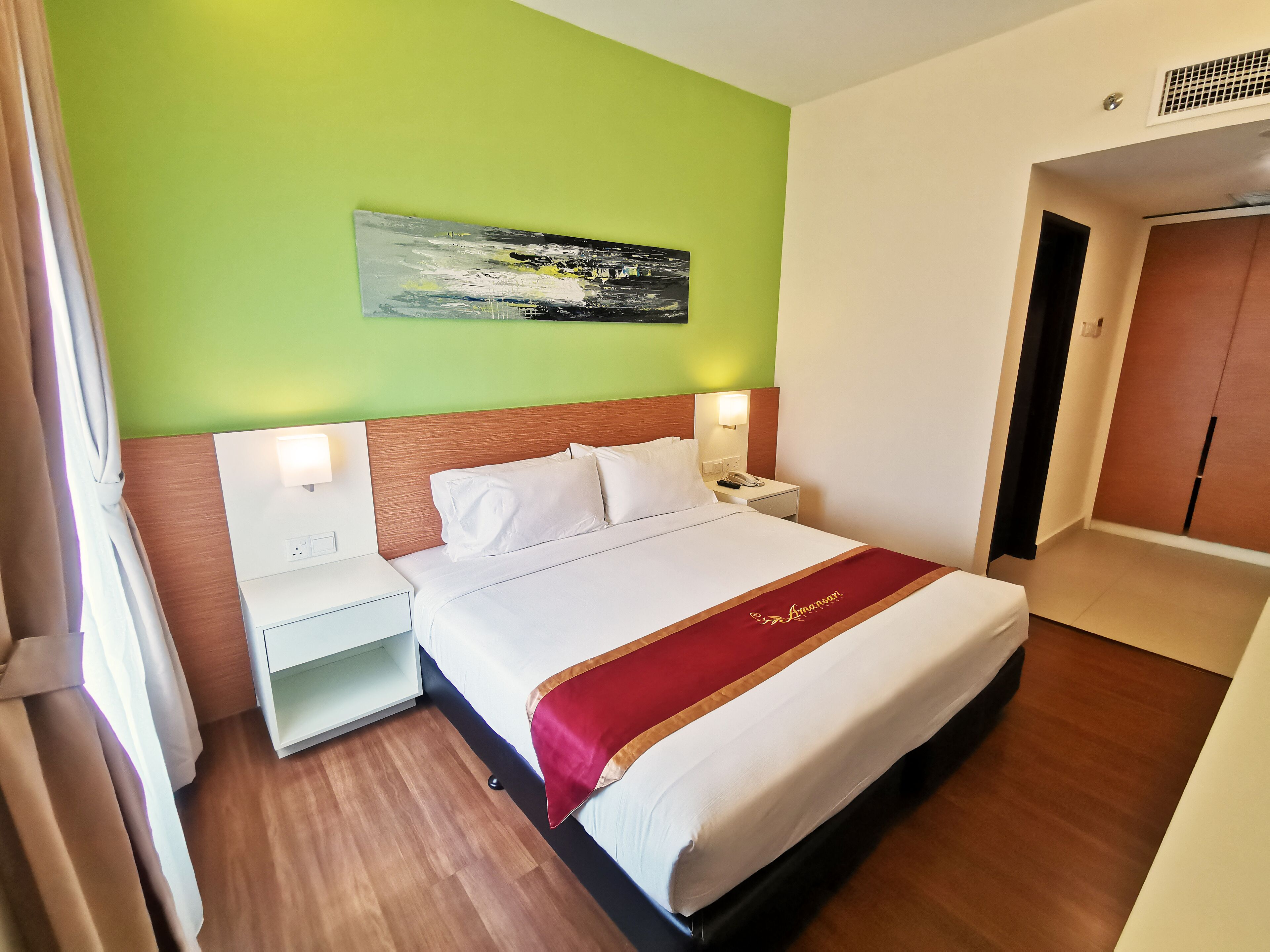 Una habitación de hotel con una cama, mesitas de noche y un cuadro en la pared, además de una puerta.