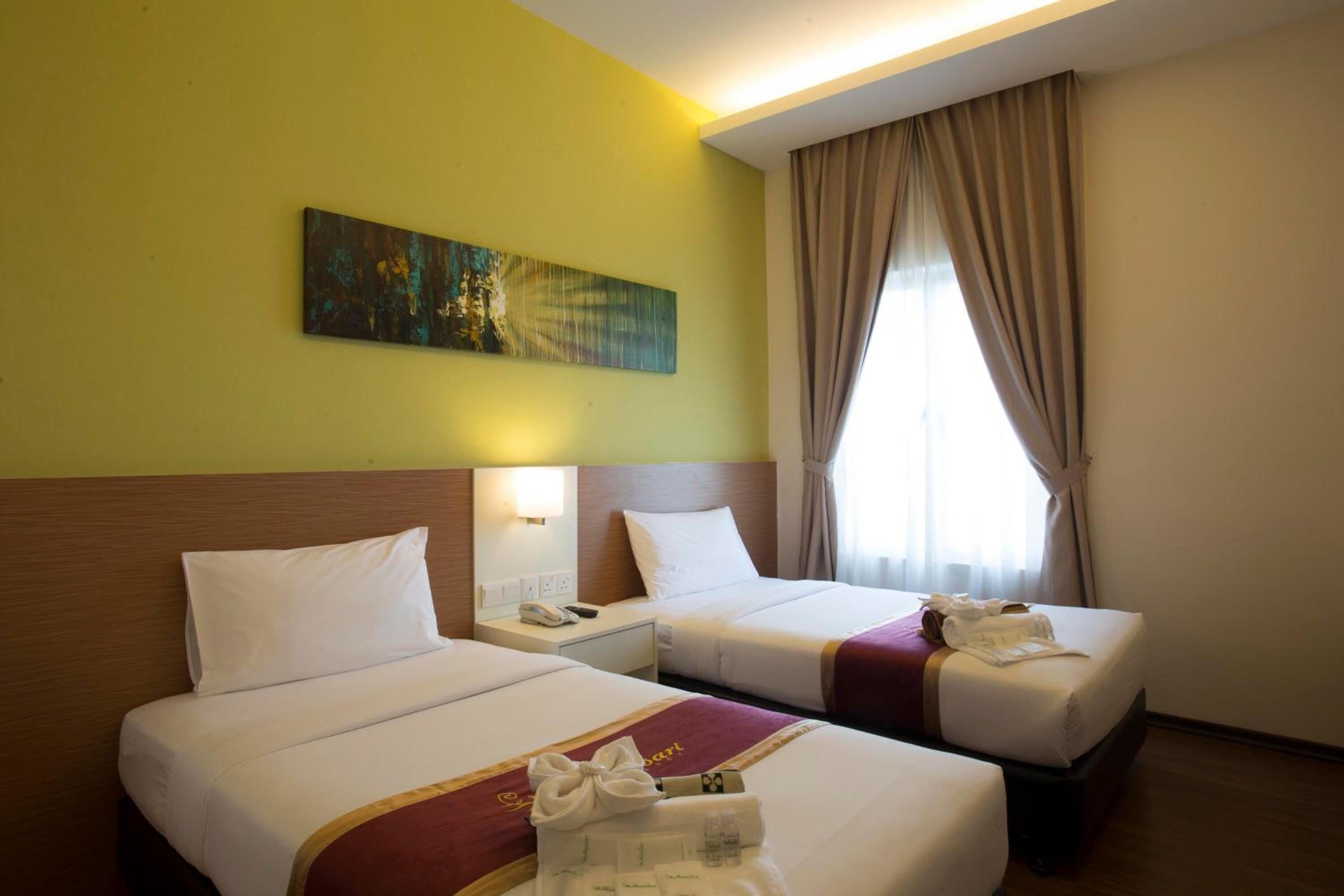 Een hotelkamer met twee bedden, een schilderij aan de muur en een raam met gordijnen.