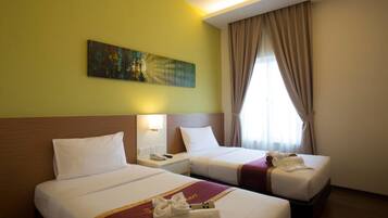A hotel room with two beds, a painting on the wall, and a window with curtains.
