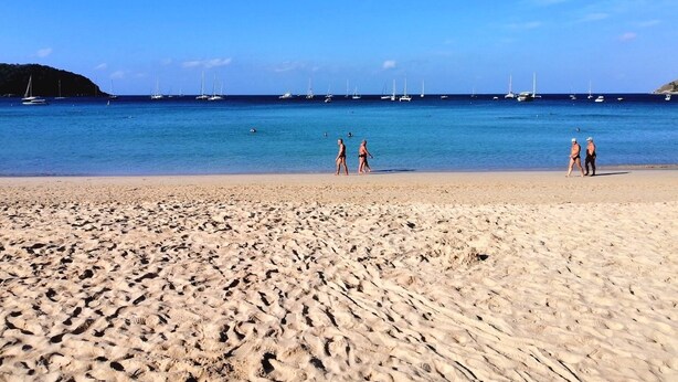 A sandy beach with footprints, a clear blue sky, and several boats in the water. - Pakta Phuket (Phuket)
