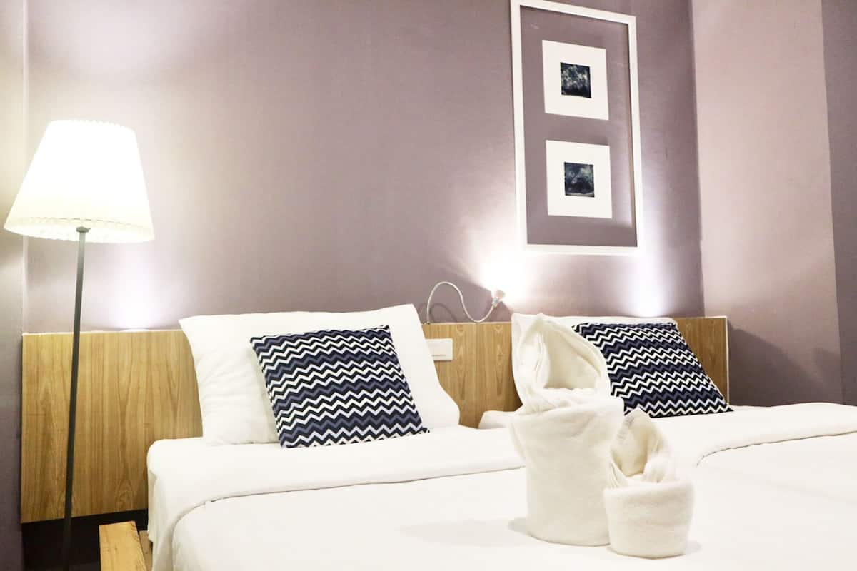 A hotel room with a bed, two pillows, a bedside lamp, and a wall-mounted picture.