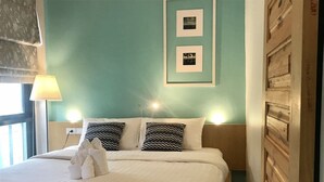 A neatly made bed with white linens, two patterned pillows, and a set of towels on the bed. There are two framed pictures on the wall above the bed. - Pakta Phuket (Phuket)