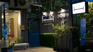 A building with a sign for 'Pak Thai' and 'Vision Institute' with contact numbers. There are potted plants and a bench outside. - Pakta Phuket (Phuket)