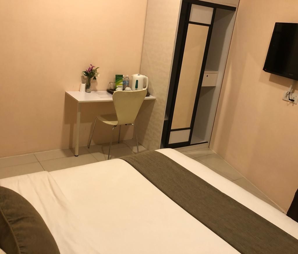 Een hotelkamer met een bed, een bureau, een stoel, een televisie en een spiegel.