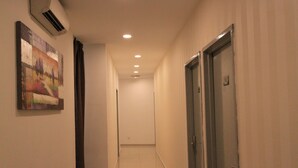 A corridor with a painting on the left, a door on the right, and a ceiling with recessed lighting. - Le Garden Hotel (Shah Alam)