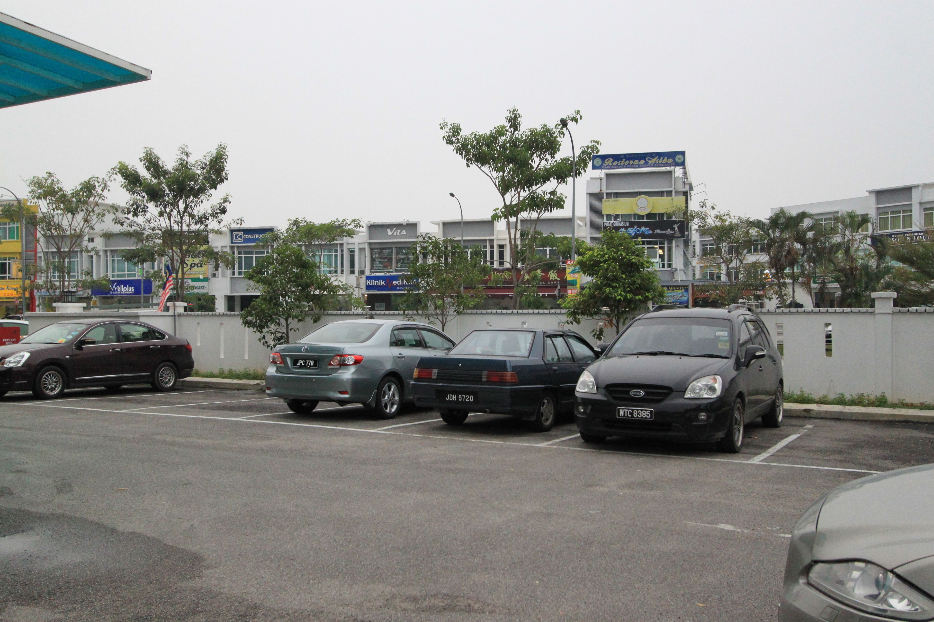 Een parkeerplaats met verschillende auto's voor een gebouw met diverse bedrijfsaanduidingen.