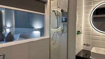 A modern bathroom with a glass shower enclosure, a vanity with a mirror, and a window with a view.