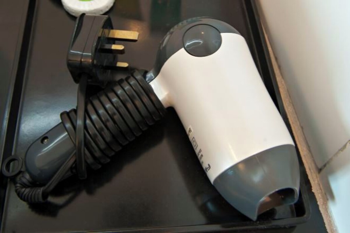 A white and gray electric kettle with a black cord on a black surface.