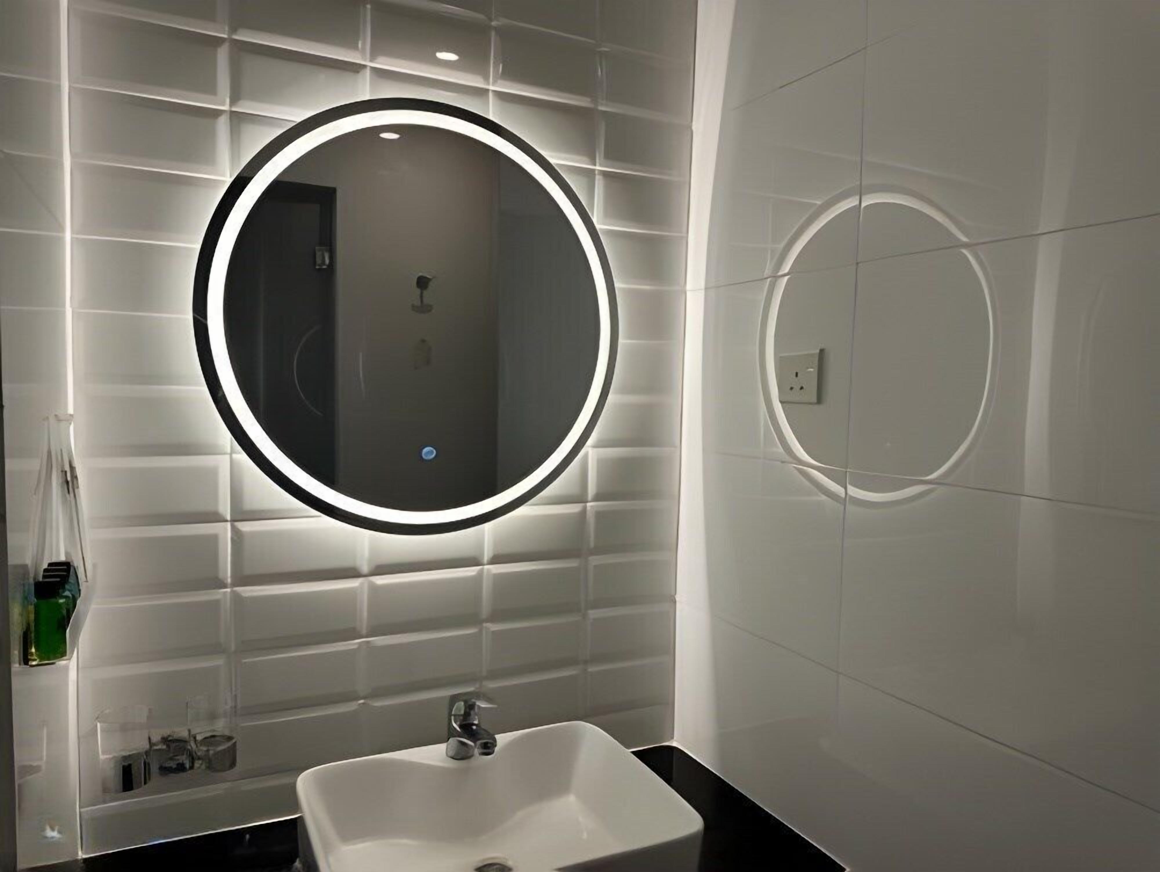 A modern bathroom with a large mirror, a sink, and a toilet.