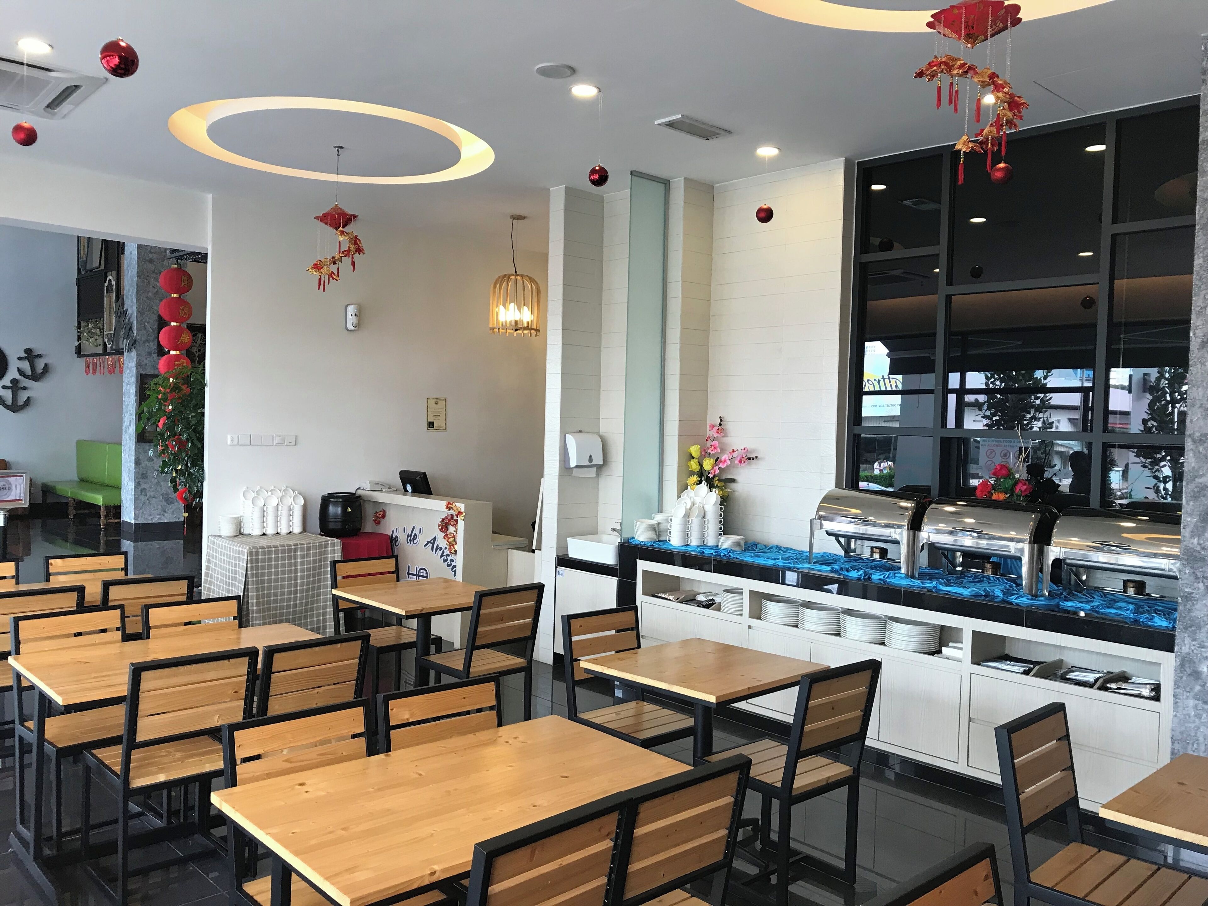 A restaurant with wooden tables and chairs, a counter with a coffee machine, and red lanterns hanging from the ceiling.
