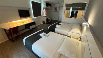 A hotel room with two beds, a desk, a TV, and a mirror.