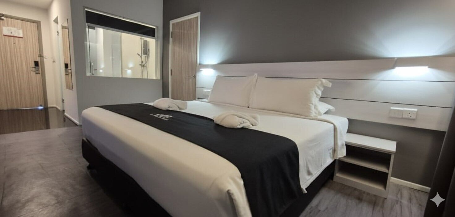 Una habitación de hotel moderna con una cama grande, una mesita de noche, un espejo y una zona de ducha.