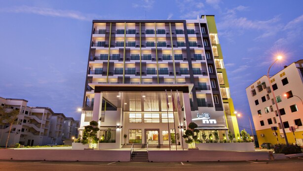 Ett hotell med flera våningar och modern design, med en framträdande entré med trappsteg och en glasfasad.