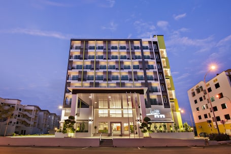 A multi-story hotel with a modern design, featuring a prominent entrance with steps and a glass facade.