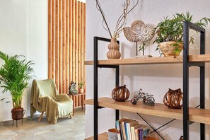 Une pièce avec une chaise en bois, une bibliothèque et des plantes en pot.