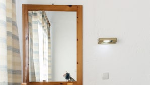 A wooden desk with a mirror, two chairs, a small trash bin, and a light switch on the wall. - Solano Hotel (Hersonissos)