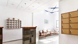 A hotel lobby with a stone fireplace, wooden lockers, and a seating area with floral chairs.