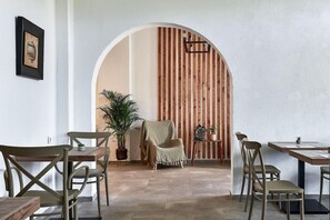 A dining area with a wooden wall, a covered chair, and a potted plant. - Solano Hotel (Hersonissos)