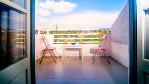 A balcony with two chairs and a table, overlooking a landscape with greenery and a clear sky. - Solano Hotel (Hersonissos)