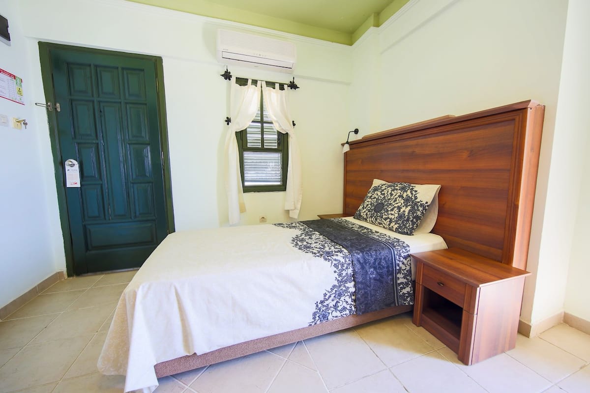 A bedroom with a bed, wooden headboard, and a nightstand.