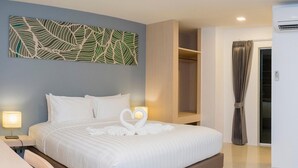 Una camera d'albergo moderna con un letto grande, un'opera d'arte a parete, un armadio a muro e un bagno con tenda.
