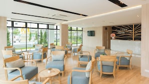 Una hall d'hotel moderna con arredi in legno e ampie finestre che offrono vista sull'esterno.