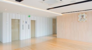 A spacious, modern hallway with wooden flooring, white walls, and a framed portrait on the right. - Trat City Hotel (Trat)