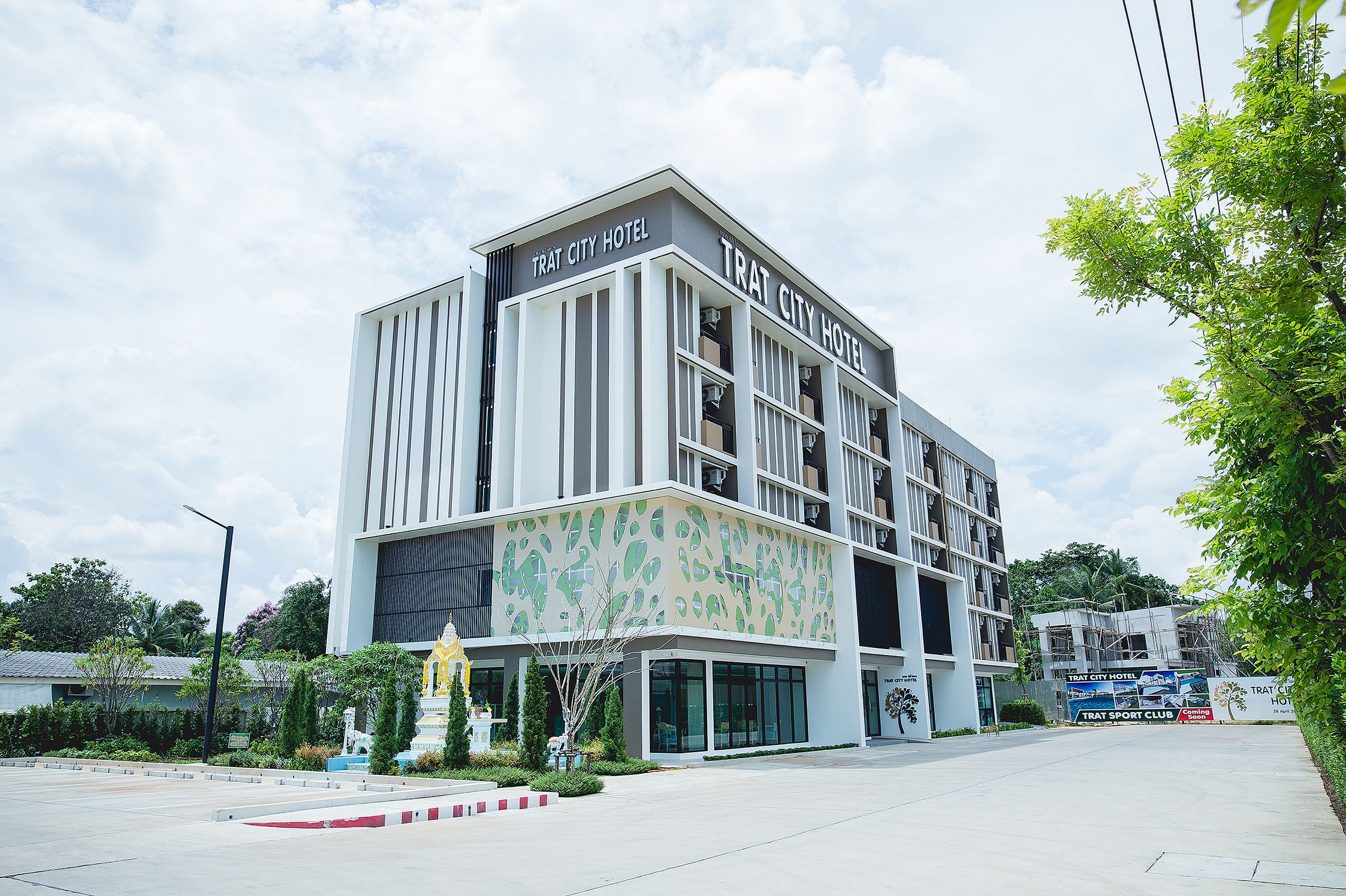 A modern hotel with a flat roof, large windows, and a sign reading "TRAT CITY HOTEL".