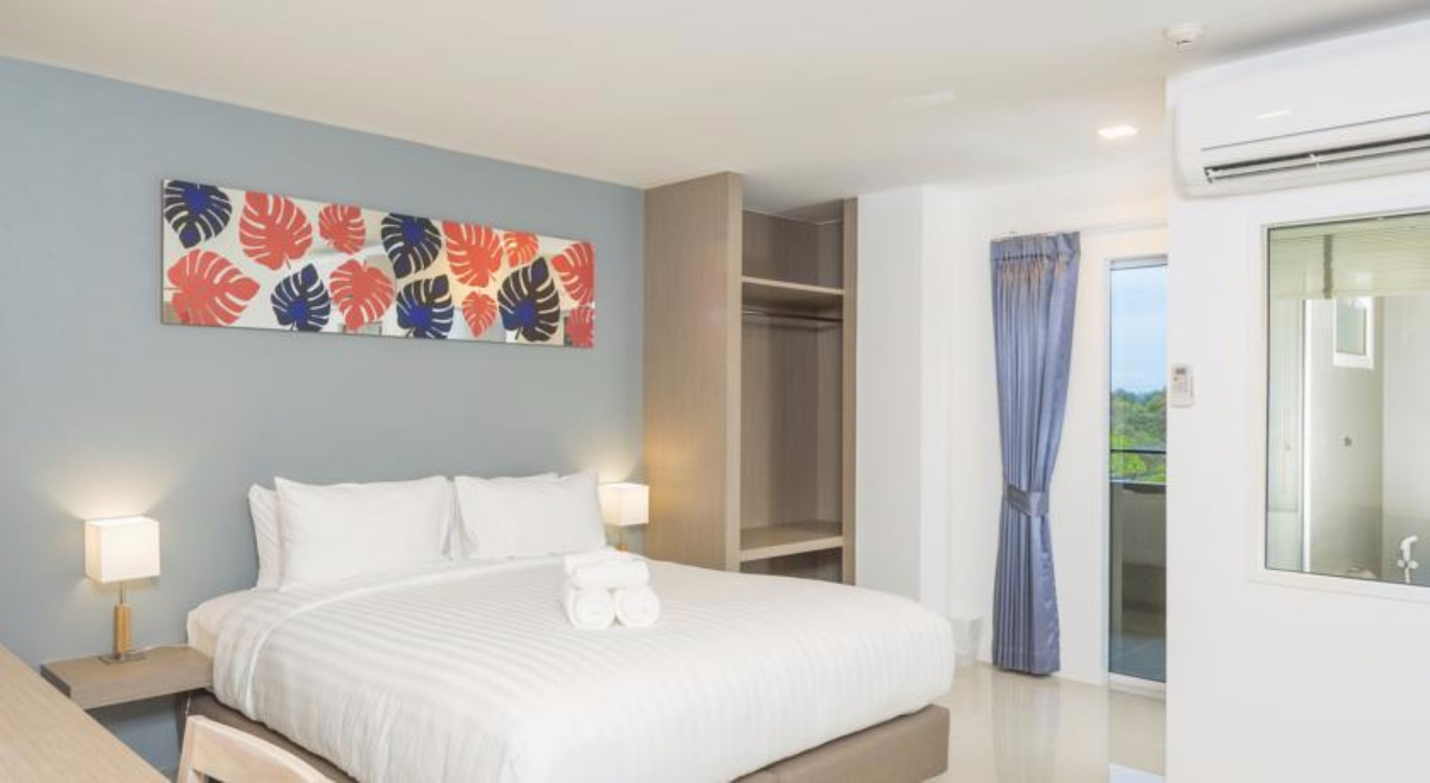 A hotel room with a bed, bedside lamps, a wardrobe, and a balcony with a view.
