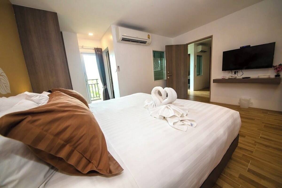 Une chambre d’hôtel avec un grand lit, un téléviseur à écran plat fixé au mur et un plancher en bois.