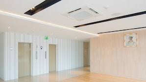 Una hall moderna di un hotel con pavimento in legno, pareti a righe e un ritratto incorniciato al muro.