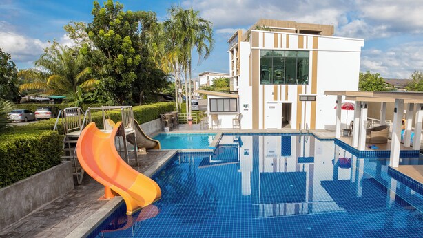 Una piscina con uno scivolo, circondata da un edificio dal design moderno e da vegetazione sullo sfondo.