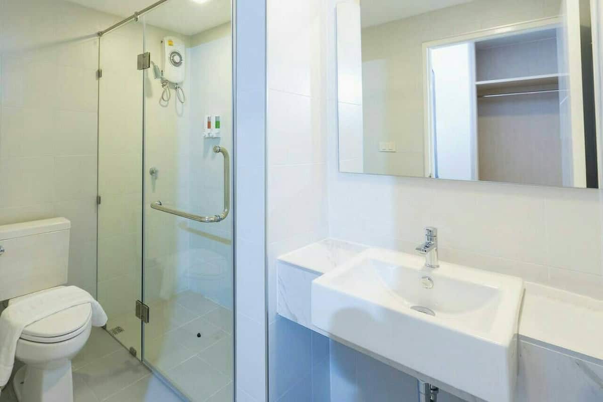 Une salle de bain avec une douche à parois de verre, un lavabo blanc et des toilettes.