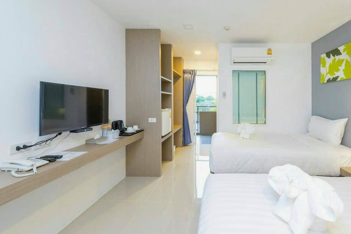 Une chambre d’hôtel équipée d’une télévision, d’un bureau avec un téléphone et une machine à café, de deux lits, d’une armoire et d’un climatiseur.