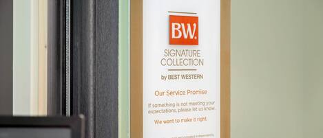 A hotel sign with the logo 'BW' and text 'SIGNATURE COLLECTION by BEST WESTERN' along with a service promise.