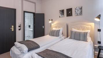 Habitación de hotel con dos camas, zona de ducha y tres cuadros colgados en la pared.