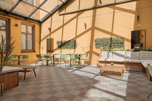 A sunlit indoor space with a checkered floor, green chairs, a wooden coffee table, and a sofa with cushions. - Hotel Hotorget, BW Signature Collection (Stockholm)