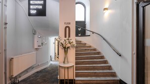 A staircase with a handrail, a sign indicating the floor number, and a vase with flowers on a column. - Hotel Hotorget, BW Signature Collection (Stockholm)