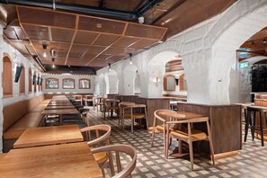 A restaurant interior with wooden tables and benches, a patterned floor, and a high ceiling with ventilation. - Hotel Hotorget, BW Signature Collection (Stockholm)