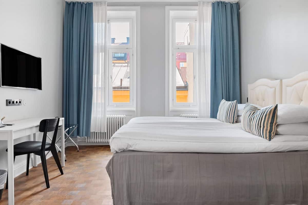 Ett sovrum med en säng, ett skrivbord, en stol och en tv.