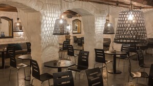 An interior with stone arches, black chairs, round tables, and hanging lamps. - Hotel Hotorget, BW Signature Collection (Stockholm)