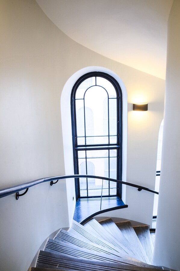 A spiral staircase with a black handrail and a window at the top.