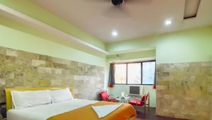 A hotel room with a bed, a small table, and a chair. - Evergreen Hotel (Mumbai)