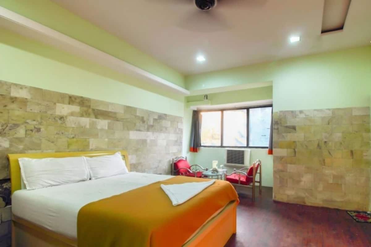 A hotel room with a bed, a small table, and a chair.