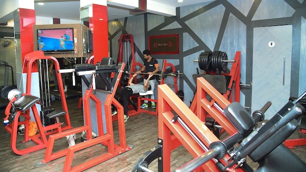 A gym with various exercise equipment, including a bench press, squat rack, and weight benches. - Evergreen Hotel (Mumbai)