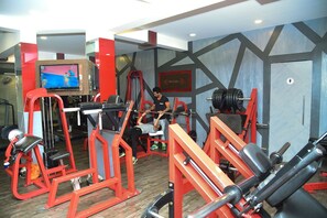 A gym with various exercise equipment, including a bench press, squat rack, and weight benches. - Evergreen Hotel (Mumbai)