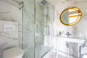 A modern bathroom with a glass-enclosed shower, a toilet, and a sink with a mirror.
